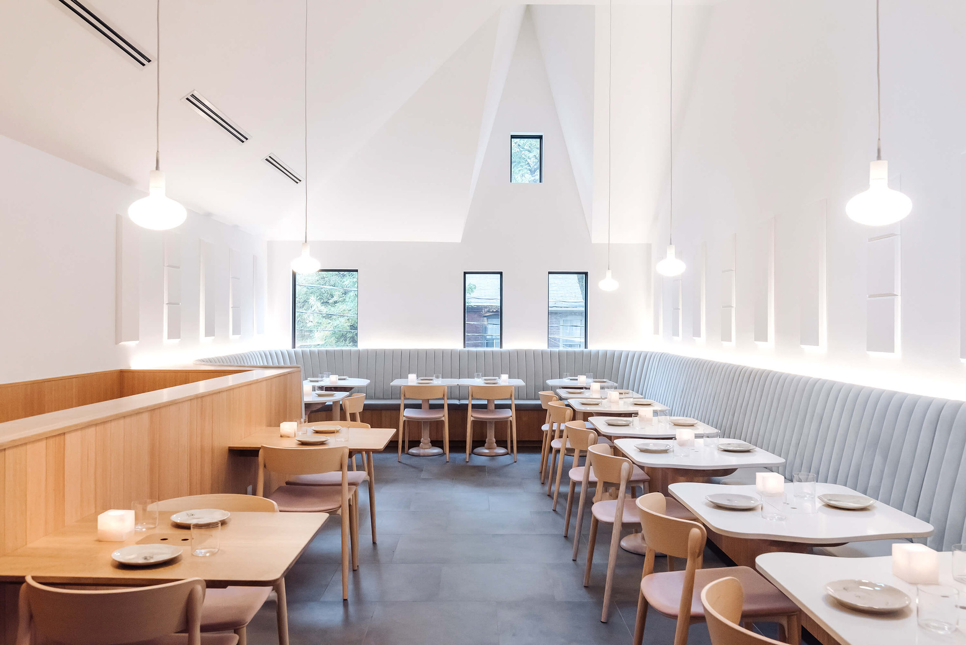 Sara restaurant dining room — minimalist white interior with banquette seating and vaulted ceiling